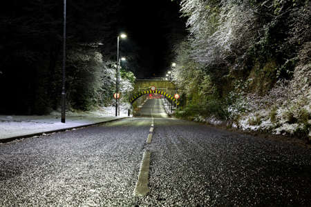 Snow scene of an old stone arch railway bridge from the middle of the roadの写真素材