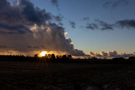 The Setting sun and storm clouds looking over a farmers fieldの写真素材