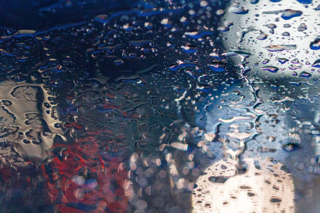 reflections of lights through rain water on a cars window screen with bokerの写真素材
