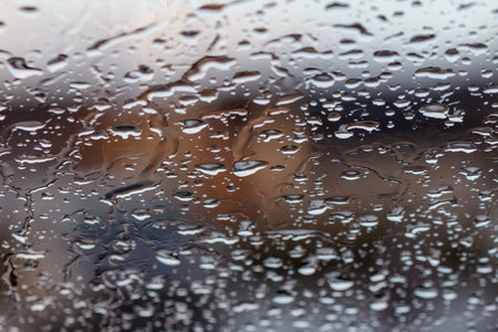 Rainwater makes lovely patterns on glass window in daytimeの写真素材