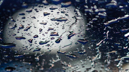 rainwater on glass  and white boker lights in the backgroundの写真素材