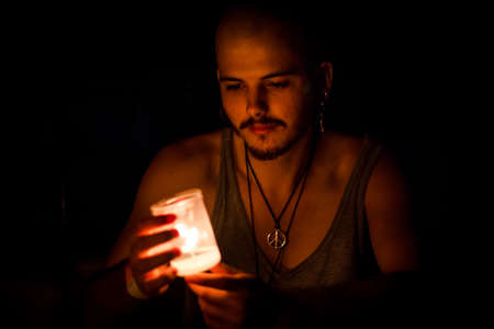 Boy with a candle in his hands in the darkness.の写真素材