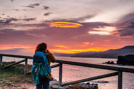 Backpacker taking a photo in sunset.の写真素材