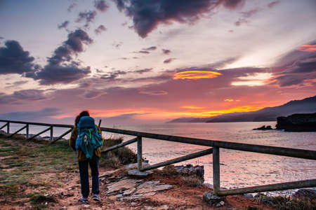 Backpacker doing hiking next to the sea in sunset.の写真素材