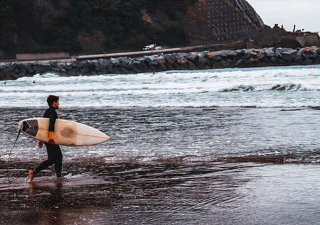 Surfer entering the water with the board under his arm.の写真素材