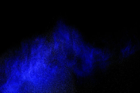 Freeze motion of blue powder exploding, isolated on black, dark background