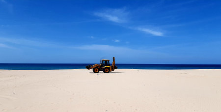 Yellow tractor on the beach with the blue sea in the background