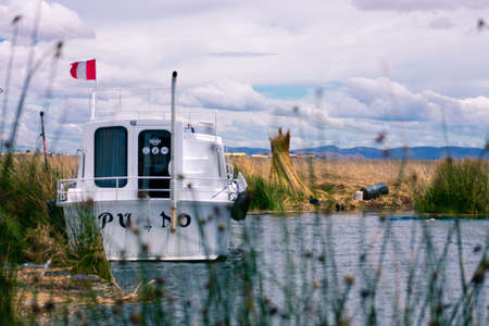 White boat with the Peruvian flag on Lake Titicaca, a floating city of the Uros, located in Puno, southern Peru.の写真素材