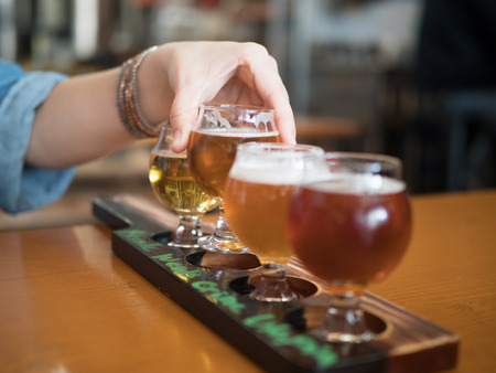 Woman reaching for flight of beers, focus on handの写真素材
