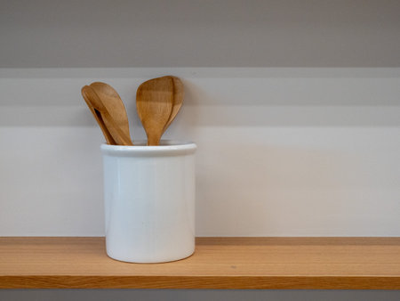 Wooden spatula and utensils in storage sitting on wooden shelf indoors