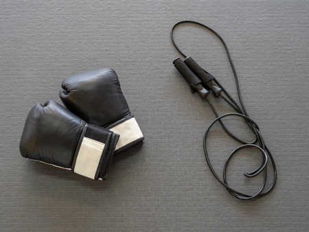 Black boxing gloves and jump rope on gym mat, ready for cross-trainingの写真素材