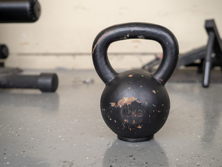 Black, 10 kg kettlebell sitting on hard floor of gymの写真素材