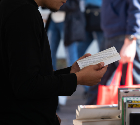 Man standing while intently reading a paperback bookの写真素材