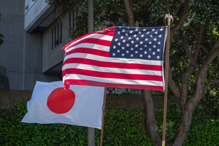 Japanese and American flags flowing in the wind outdoors in the shade