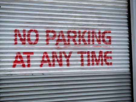 No parking at any time red spray painted warning sign on garage doorの写真素材