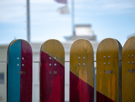 A number of teal, red, yellow weathered skateboards mounted on railing