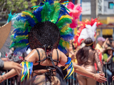 A woman wearing Aztec feather head wear, marching down a paradeのeditorial素材