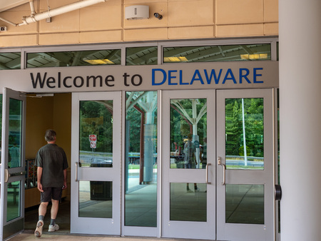 Welcome to Delaware sign above a rest area stop, man walking inのeditorial素材