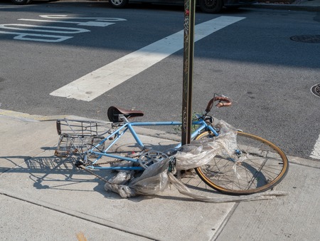 Trashed bike wrapped in garbage broken on street cornerの写真素材