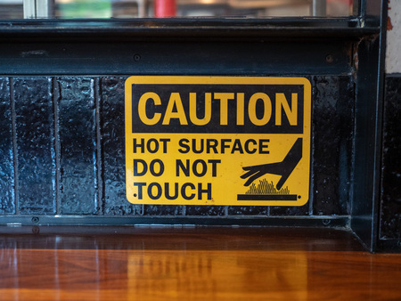 Caution hot surface, do not touch sign in front of a grill at a restaurantの写真素材