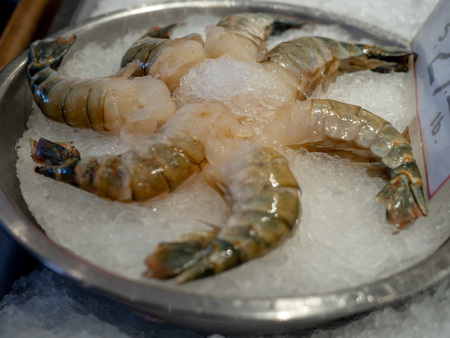 Group of raw shrimp sitting in circular bowl filled with ice at a fisher man s marketの写真素材