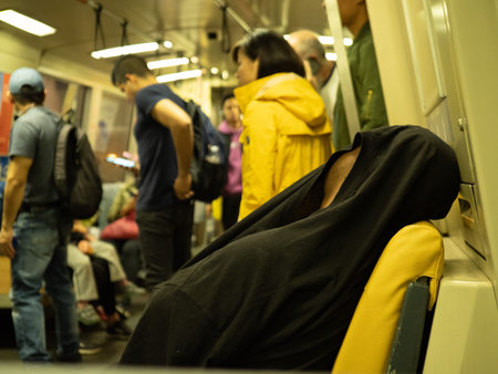Man sleeps with shirt over his head on a crowded BART subway car