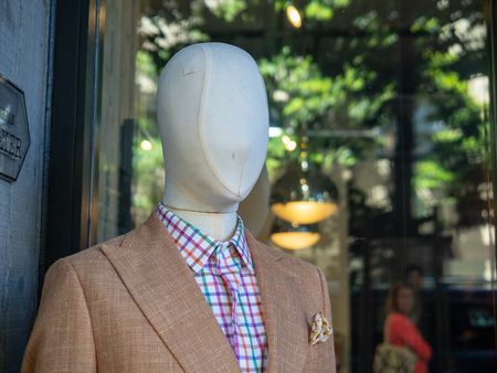 Male mannequin wearing a brown suit jacket posting out side of designer storeの写真素材
