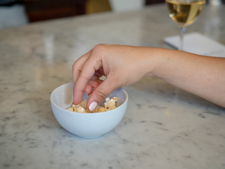 Woman manicured hand inside a small bowl of popcorn with wineの写真素材