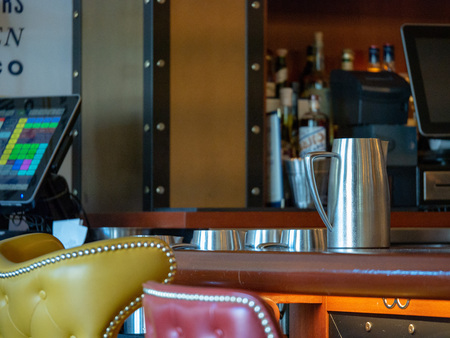 Steel water pitcher sitting on bar counter near point of service machineの写真素材