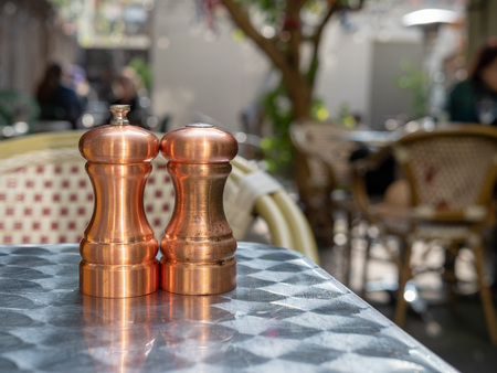 Cooper salt and pepper shakers and grinders sitting outdoors on  restaurant tableの写真素材