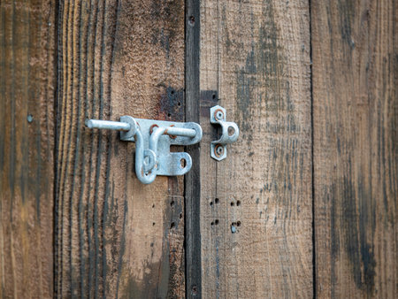 Steel rusty metal latch lock hanging outdoors on wooden double door