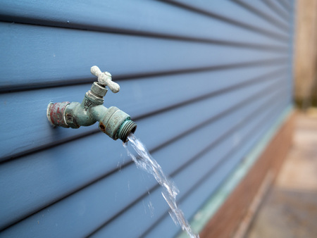 Water streaming out of outdoor faucet for garden hose outdoorsの写真素材
