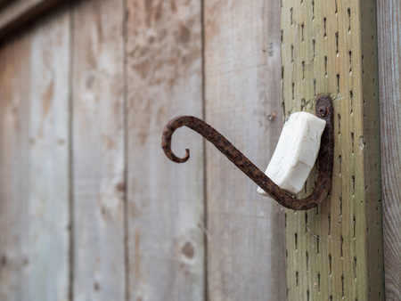 Rusty hook with bar of soap resting in an outdoor fence areaの写真素材
