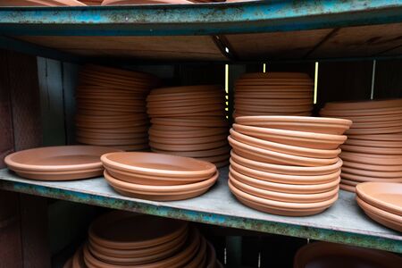 Stack of brown planter saucers on shelves at outdoor nurseryの写真素材