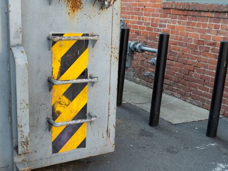 Warning tape pattern on waste container outside at side of buildingの写真素材