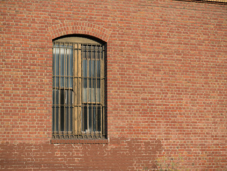 Rusty gated window outside of brick warehouseの写真素材