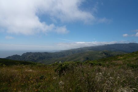Hills and bushes in ocean side trail with clouds and natureの写真素材