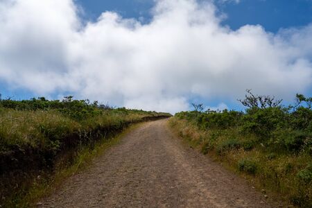 Winding dirt trail road going into horizon with clouds in natureの写真素材
