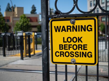 Warning look before crossing yellow warning sign at train stationの写真素材