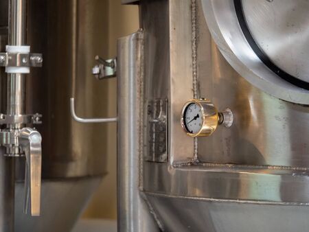 PSI gauge at low pressure on fermentation tank in busy breweryの写真素材