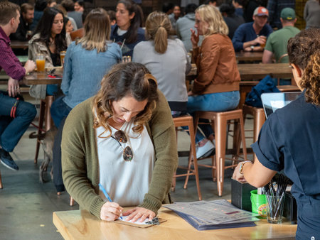 Woman signing receipt at register at popular and crowded bar