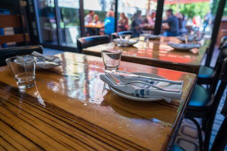 Table setting of cups, napkins, plates, and utensils in casual restaurantの写真素材