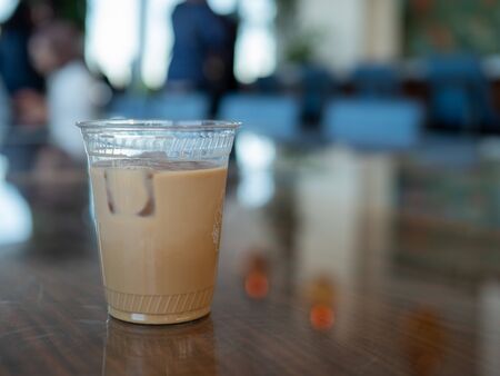Iced coffee inside clear plastic cup sitting on counter of busy coffee shopの写真素材