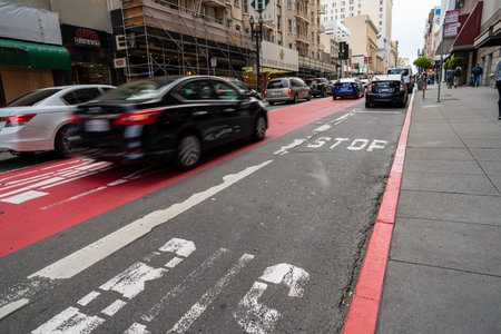 Busy city street in rush hour with cars driving in motion near a protected red bus laneのeditorial素材