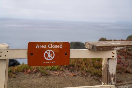 Area closed no hiking or access sign on fence block entry to cliff side of ocean waterの写真素材