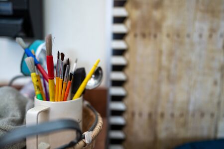 Cup of small paint brushes and art supplies in a creative art studioの写真素材