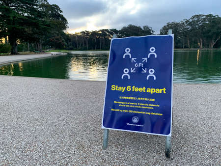San Francisco, California March 23, 2020: Stay 6 feet apart social distancing guidelines for coronavirus COVID-19 in multiple languages and logo in Golden Gate Park in San Francisco in front of lakeのeditorial素材