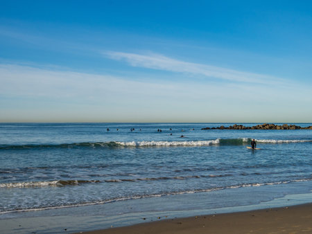 Surfer embarks into ocean to ride small waves on beachの写真素材