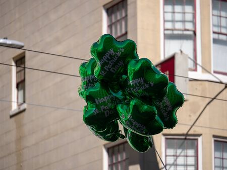 Festive happy St Patrick s Day green shamrock balloons floating in urban settingの写真素材