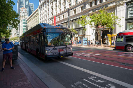 Muni bus Fulton line 5 on moving past person on Market Street shopping districtのeditorial素材